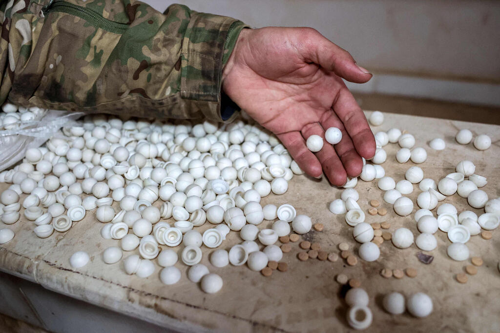 לוחם מורד סורי בוחן כדורי קפטגון (שם מסחרי של התרופה הפסיכוסטימולנטית פנאתילין) שיוצרו במעבדת ייצור מאולתרת בוילה חקלאית בעיירה אל-דימאס, כ-27 קילומטרים צפונית-מערבית לדמשק, ב-22 בדצמבר 2024