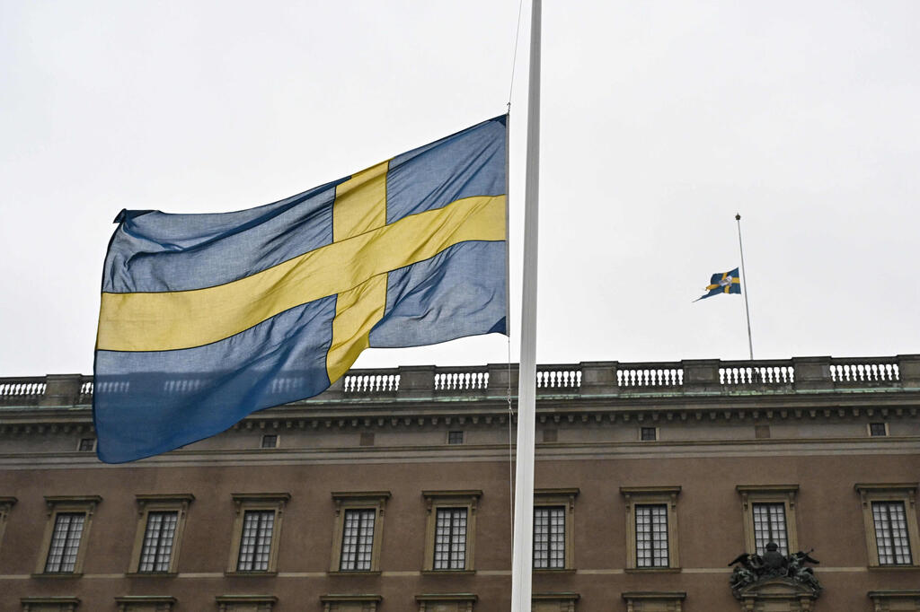 The Swedish parliament approved the legislation enabling authorities to strip migrants of residence permits (Photo: Jonas EKSTROMER / TT NEWS AGENCY / AFP) שבדיה דגל חצי התורן טבח אורברו
