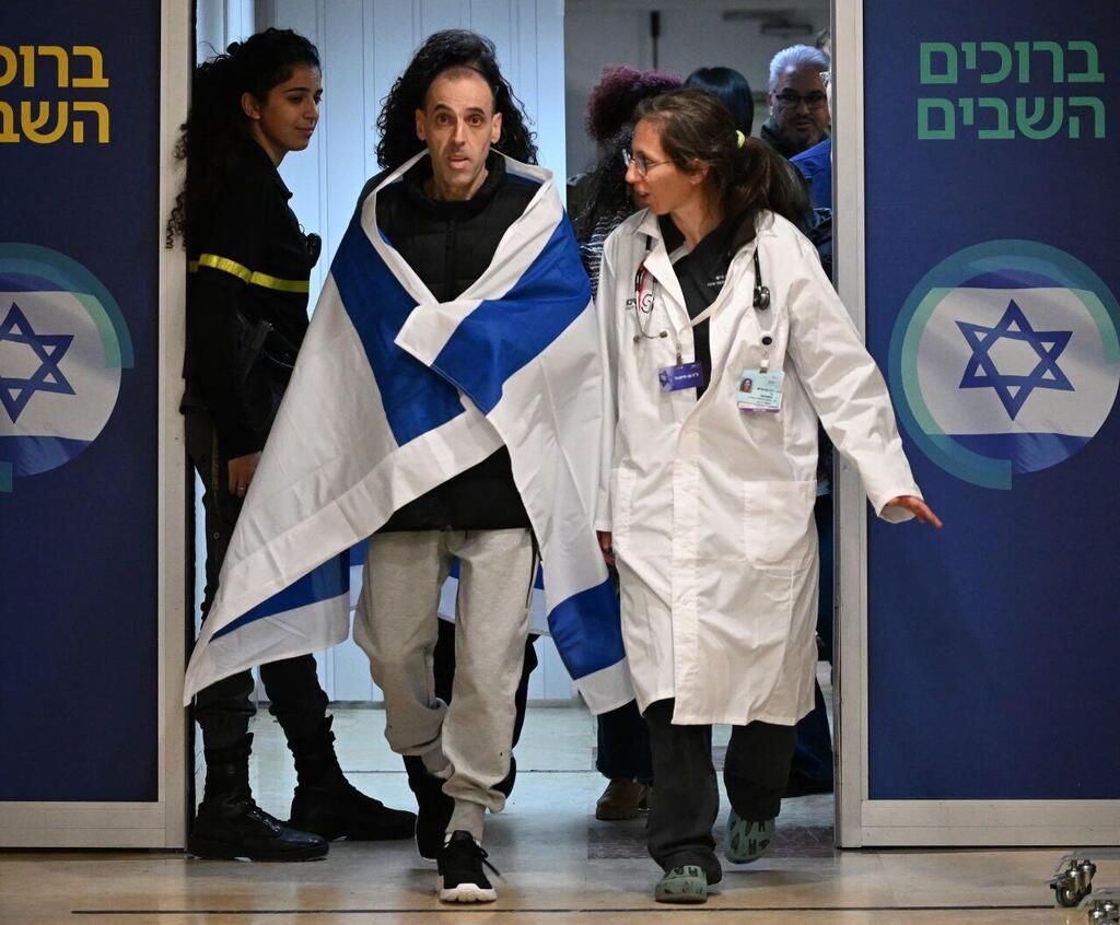 Eli Sharabi arrives at the hospital draped in the Israeli flag after his release from captivity (Photo: GPO) אליהו (אלי) שרעבי עטוף בדגל ישראל, עם הגעתו לבית החולים שיבא