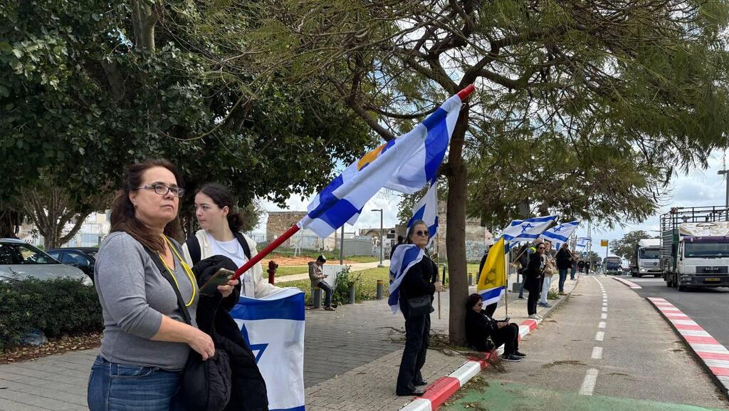 הדרך אבו כביר אזרחים מוכנים עם דגלי ישראל במהלך קבלת גופות החטופים
