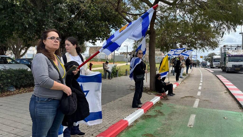 הדרך אבו כביר אזרחים מוכנים עם דגלי ישראל במהלך קבלת גופות החטופים