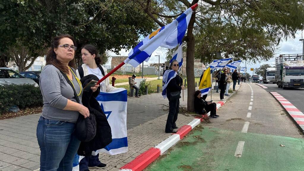 הדרך אבו כביר אזרחים מוכנים עם דגלי ישראל במהלך קבלת גופות החטופים