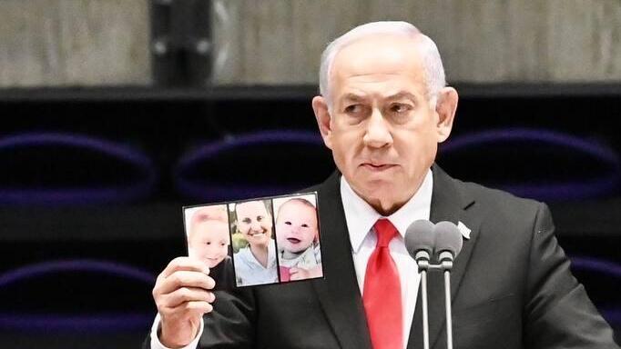 ראש הממשלה בנימין נתניהו מחזיק את תמונת של משפחת ביבס שנרצחו בשבי חמאס, במהלך טקס סיום קורס קצינים קרביים