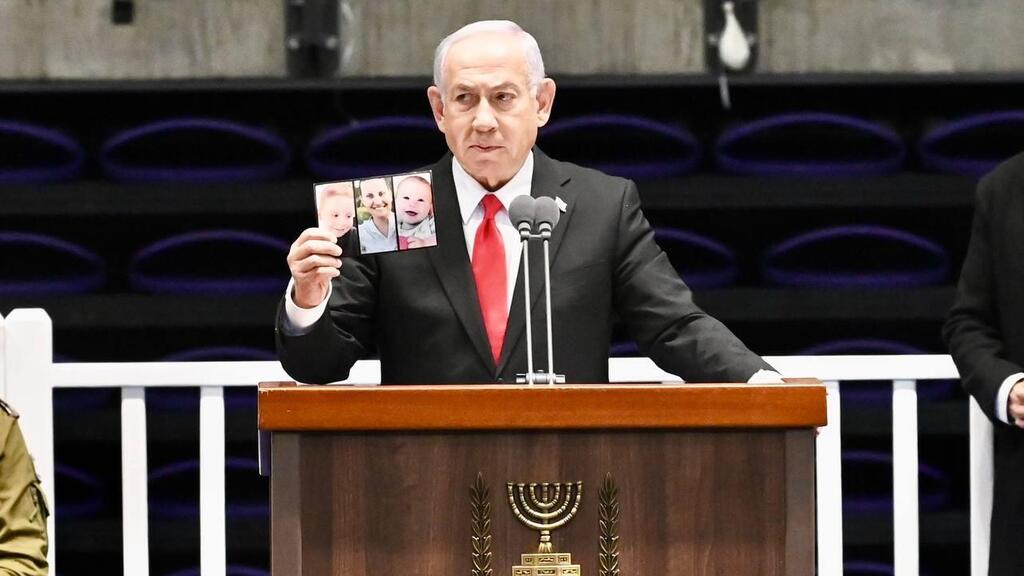 ראש הממשלה בנימין נתניהו מחזיק את תמונת של משפחת ביבס שנרצחו בשבי חמאס, במהלך טקס סיום קורס קצינים קרביים