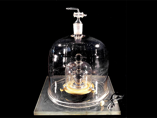 The standard kilogram weight, housed within protective glass enclosures