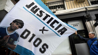 אוהדים עם השלט "צדק לאלוהים" בזמן המשפט בנוגע למותו של מראדונה