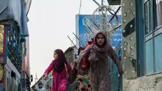 At the Torkham border between Afghanistan and Pakistan, Afghan girls weave through parked trucks, carrying contraband items 