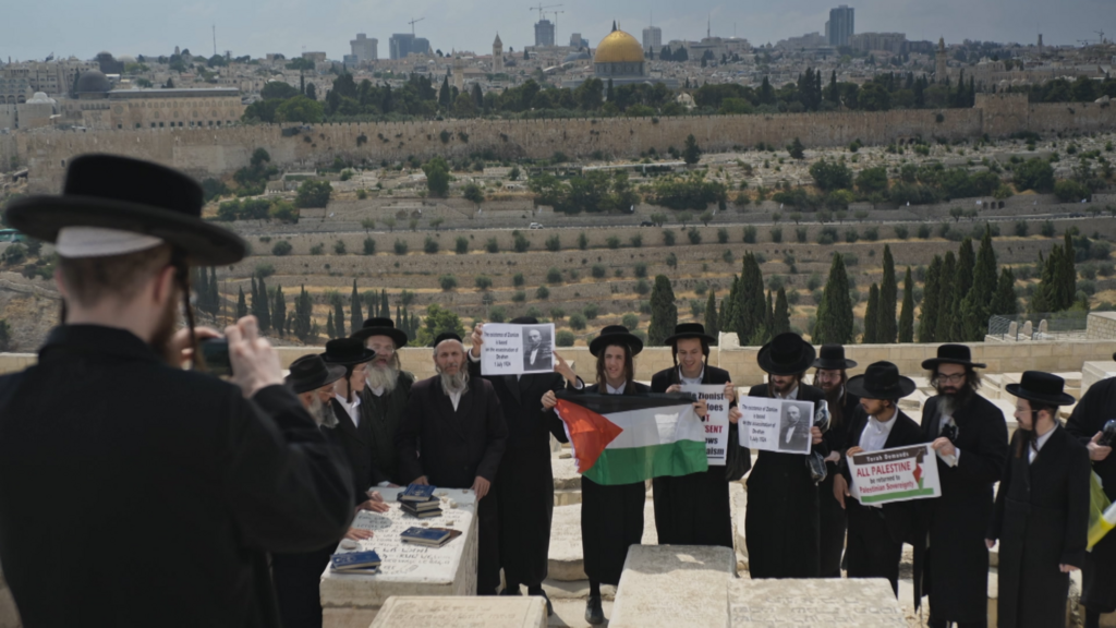 אנשי נטורי קרתא אוחזים דגל פלסטיני ומסרים אנטי-ציוניים בקברו של דה האן