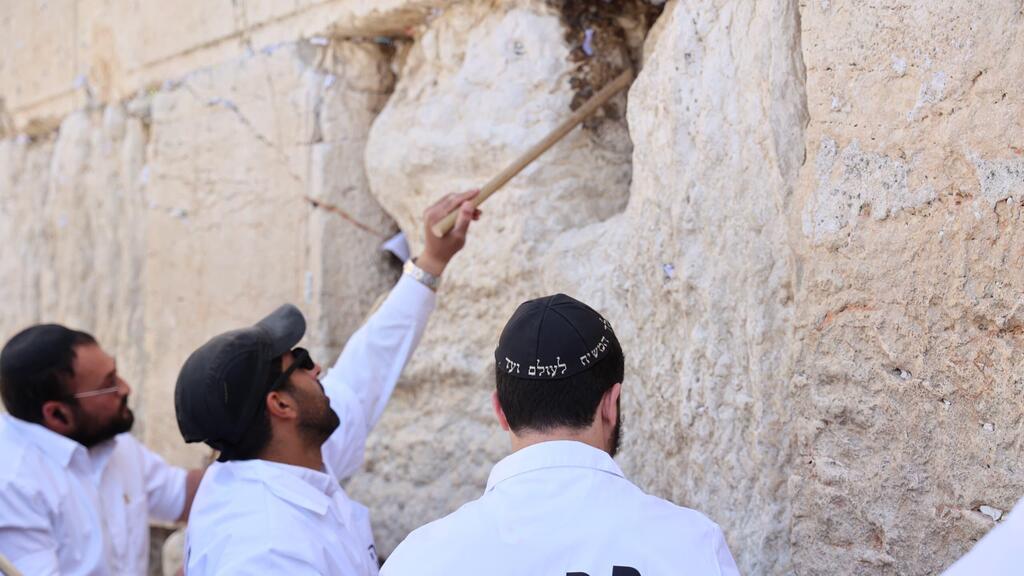 מוציאים פתקים מהכותל המערבי באמצעות מקלות עץ