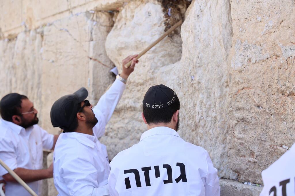 מוציאים פתקים מהכותל המערבי באמצעות מקלות עץ