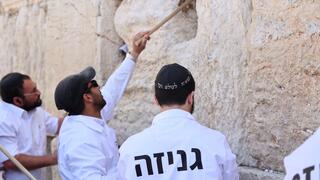 מוציאים פתקים מהכותל המערבי באמצעות מקלות עץ