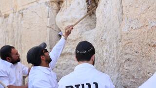 מוציאים פתקים מהכותל המערבי באמצעות מקלות עץ