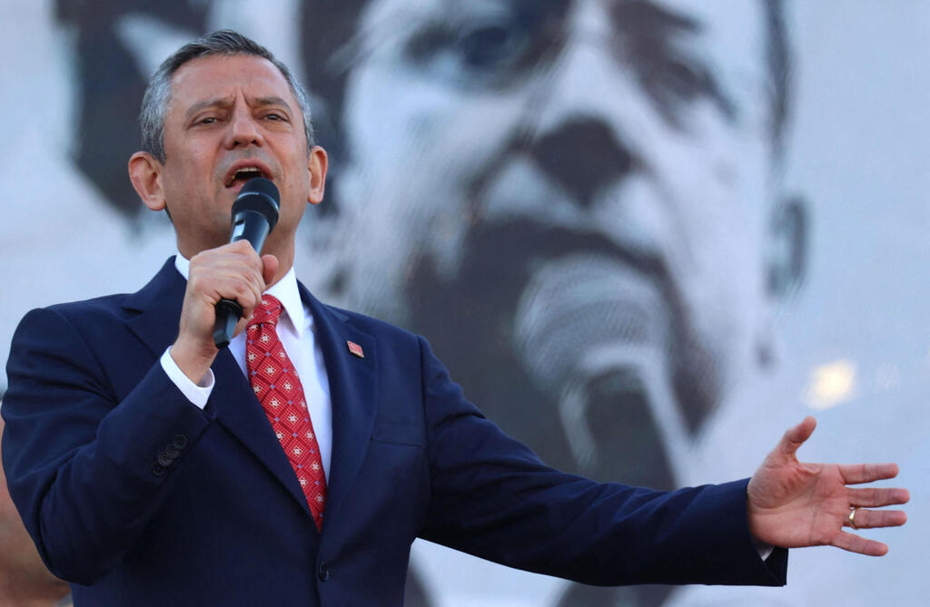 Opposition leader Özgür Özel, with a photograph of Istanbul Mayor Ekrem İmamoğlu, who was arrested last year, behind him. 'Only cowards act this way!' (Photo: Adem ALTAN / AFP) אוזגור אוזל יו"ר מפלגת האופוזיציה CHP ב טורקיה