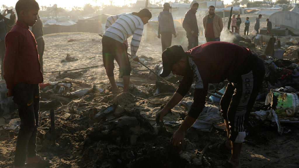עזתים בודקים נזק באתר בו תקפה ישראל בחאן יונס