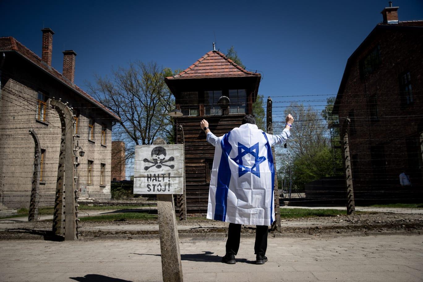 נצח ישראל,עטוף בדגל כחול -לבן ,מול גדרות אושוויץ