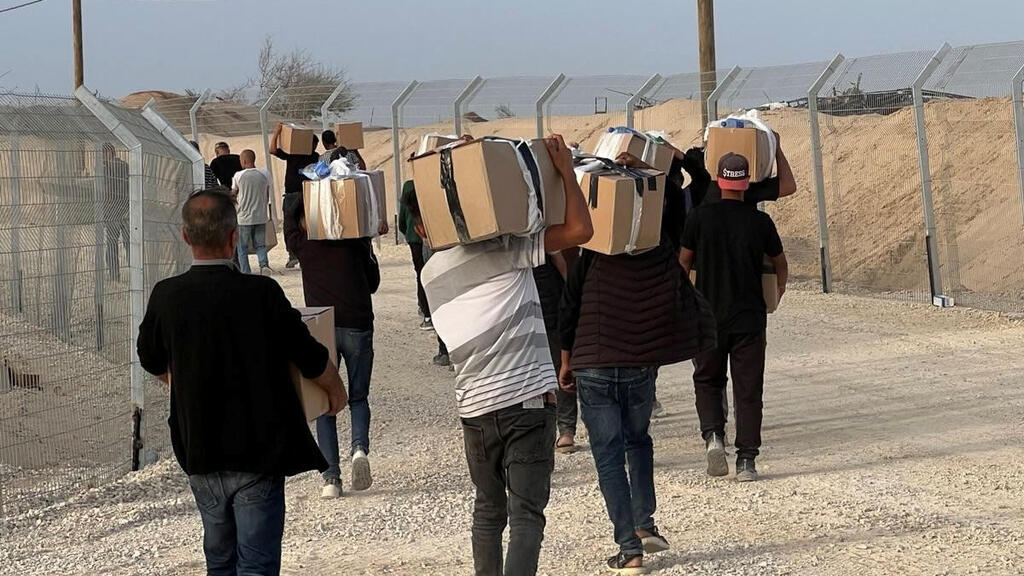 Палестинцы с коробками, полученными в Рафиахе (Фото: Gaza Humanitarian Foundation/Handout via REUTERS) עזתים הולכים לקבל חבילות סיוע המוניטרי ברפיח