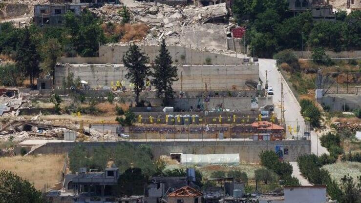 Hezbollah flags fly over a cemetery deep inside Lebanese territory, seen from the Israeli side of the border. The site, marked by yellow banners and guarded by fencing, serves as a burial ground for Hezbollah fighters (Photo: Ziv Koren) ראיון עם אל"מ אבי מרציאנו, מפקד חטיבת חירם היוצא