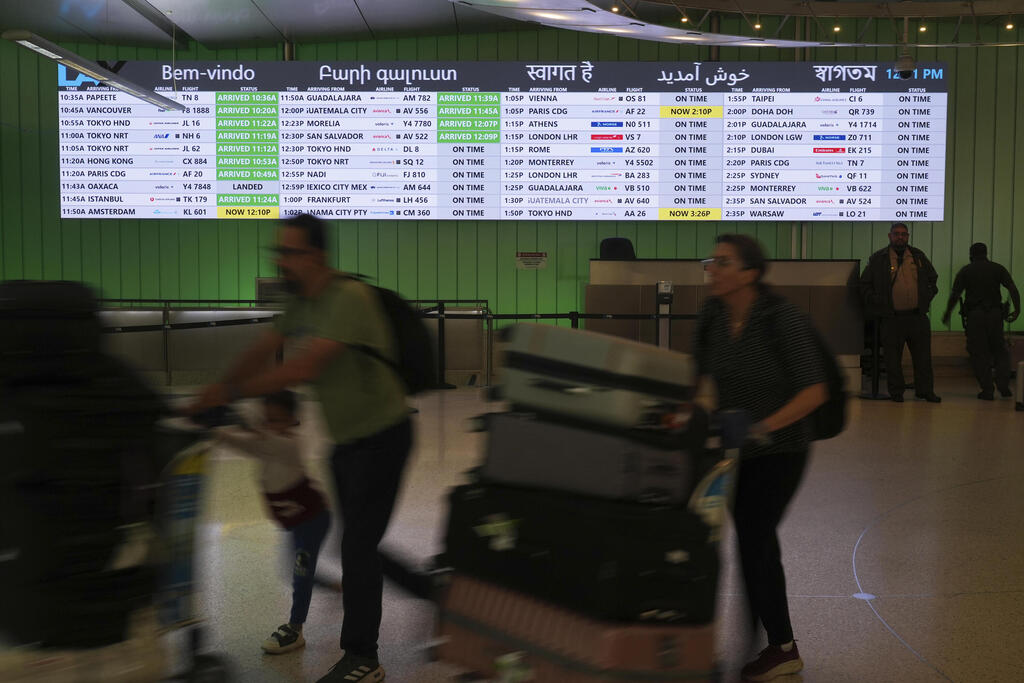 Travelers pass an Arrivals board displays greetings in multiple languages at the Los Angeles International Airport 