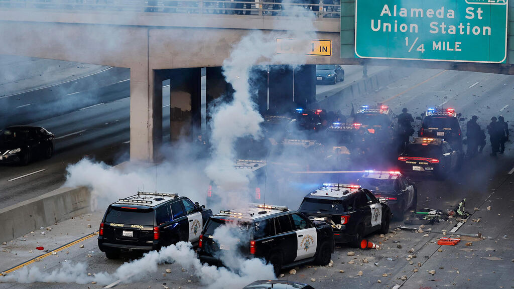 Police take refuge from rioters under highway bridge (Photo: Mario Tama / Getty Images North America / AFP) ארה"ב קליפורניה לוס אנג'לס מהומות בעקבות מעצר מהגרים בלתי חוקיים