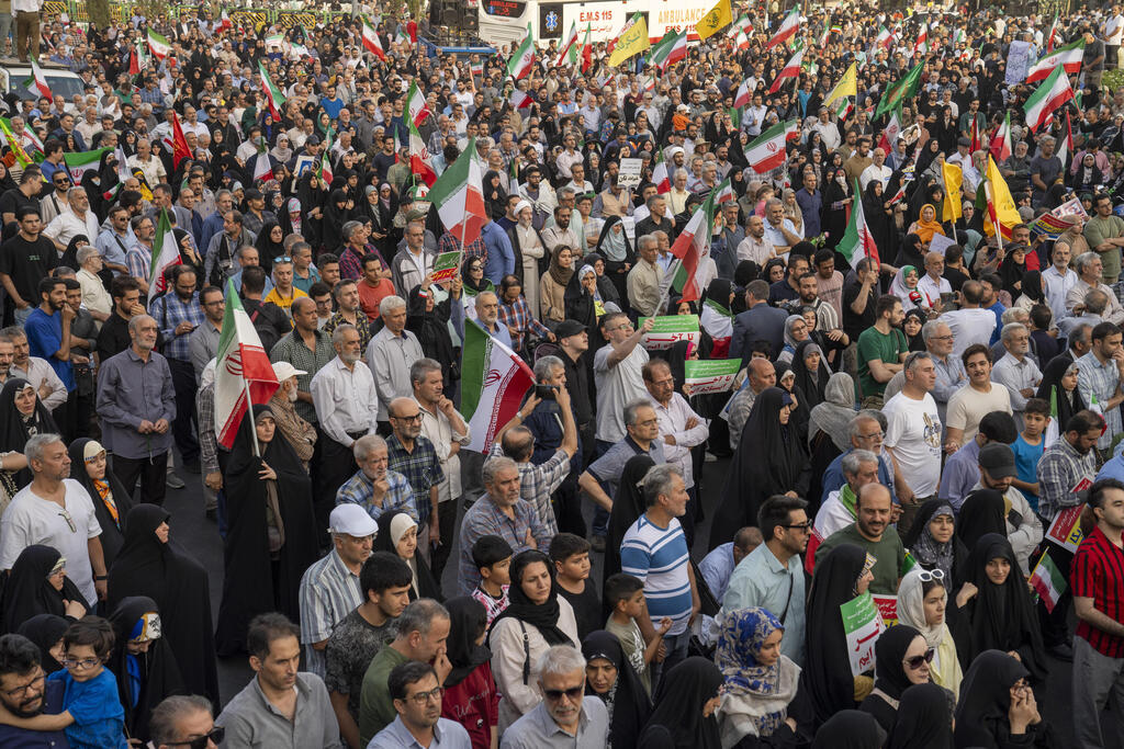 Demonstrators wave flags and cheer during a protest against Israeli and American attacks on Iran on Tuesday 