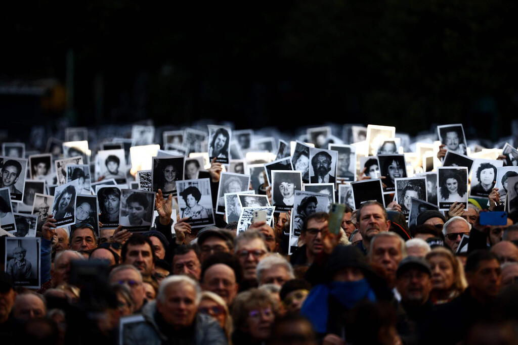 People hold pictures of victims during a ceremony to commemorate the anniversary the Mutual Israelite Association of Argentina (AMIA) bombing attack in Buenos Aires on July 18, 2024 