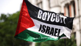 פעילים פרו פלסטינים פרו-פלסטינים מ Palestine Action עם דגל BDS הקורא ל חרם על ישראל בהפגנה מחוץ לבית המשפט ב לונדון נגד הכרזה על הארגון כארגון טרור בריטניה 