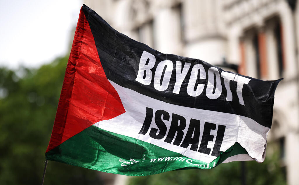 פעילים פרו פלסטינים פרו-פלסטינים מ Palestine Action עם דגל BDS הקורא ל חרם על ישראל בהפגנה מחוץ לבית המשפט ב לונדון נגד הכרזה על הארגון כארגון טרור בריטניה 