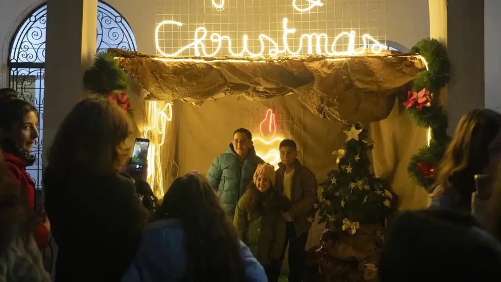 People pose for the photo next to Christmas decoration after attending a Christmas mass at the church of St. George, in Maaloula, some 60 km northern Damascus, Syria