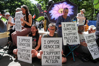 Demonstrators hold signs during a protest calling for the de-proscription of the Palestine Action group, at St Peter's Square in Manchester, Britain