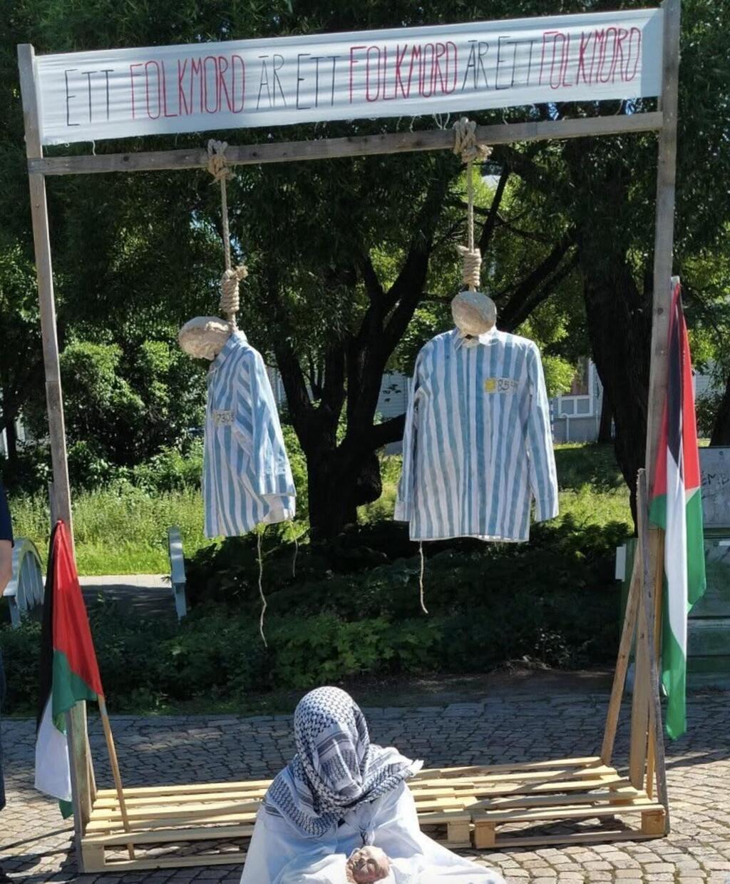 Mannequins dressed in Holocaust-era concentration camp uniforms hang from a gallows as part of a controversial pro-Palestinian display in Umeå, Sweden, on July 19, 2025. The exhibit, which includes Palestinian flags and a banner reading 'Genocide is genocide is genocide,' drew widespread condemnation for invoking Holocaust imagery (Photo: via social media) המיצג נגד יהודים