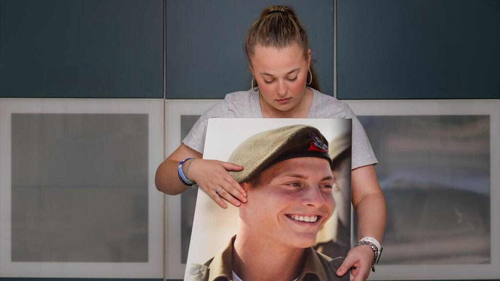 Eliora Rosenfeld holding a photo of her brother Yisrael Natan Rosenfeld (Photo: Yaron Brener) אליאורה רוזנפלד - בן זוגה הלל שמואל סעדון ז"ל ואחיה ישראל נתן רוזנפלד ז"ל נפלו במלחמה