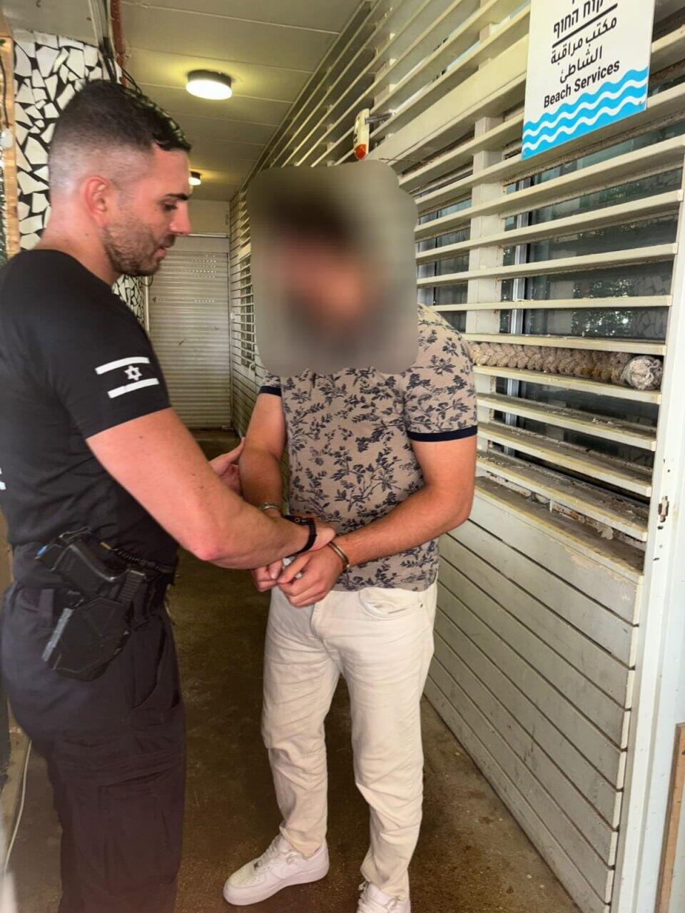A police officer detains a man suspected of filming underage girls inside the women’s changing rooms at Frishman Beach in Tel Aviv, Israel, on July 25, 2025. Authorities later confirmed the suspect is an employee of the Turkish Embass (Photo: Israel Police) תושב זר נעצר בחשד שצילם קטינות במלתחות הנשים בחוף פרישמן