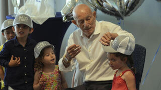 Harold Terens gifts customized hats to his great grandchildren during his 102 birthday party Saturday, July 26, 2025, in Delray Beach, Fla. 
