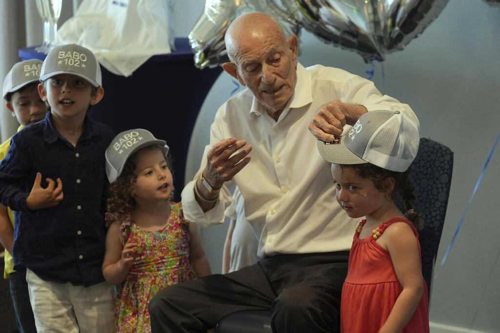 Harold Terens gifts customized hats to his great grandchildren during his 102 birthday party Saturday, July 26, 2025, in Delray Beach, Fla. 