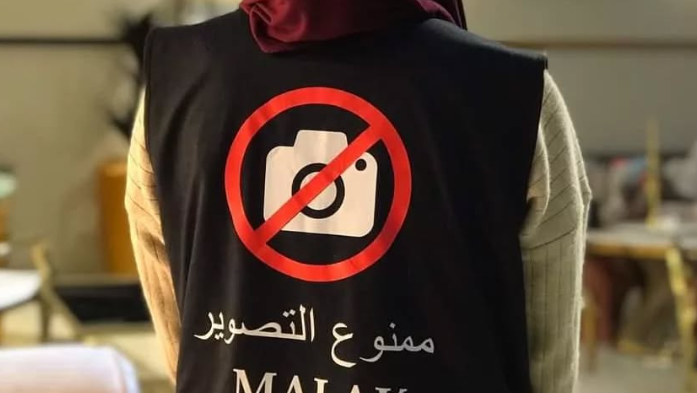 A woman wearing a vest labeled 'No filming allowed' פינת יא אללה ליאור בן ארי איסור צילומים ב חתונות אלג'יריה