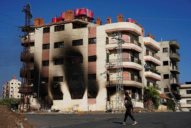 A bedouin fighter walks near a burnt building after sectarian clashes escalated on Saturday in Syria's predominantly Druze region of Sweida, with machinegun fire and mortar shelling ringing out after days of bloodshed as the Islamist-led government struggled to implement a ceasefire, in Sweida, Syria, July 19, 2025