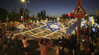 דגל ישראל עם תמונות החטופים מונף מול ישיבת הקבינט