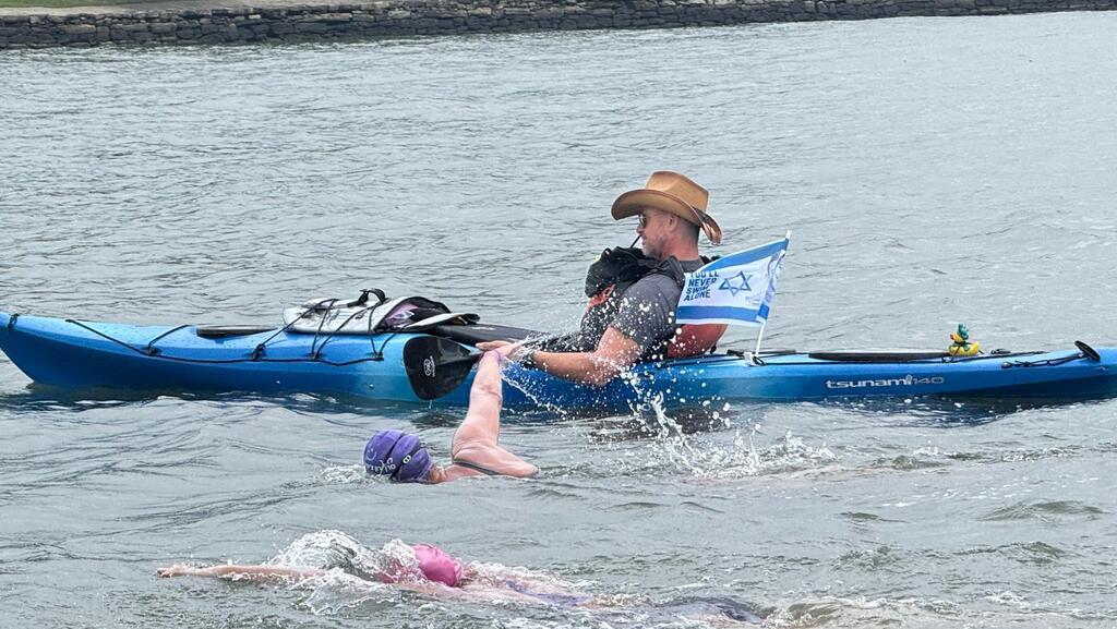 Debbie during the swim, alongside a boat flying the Israeli flag and bearing Yaron’s photo
