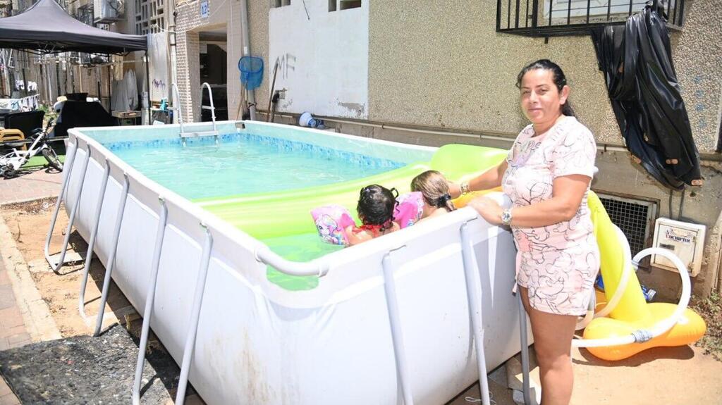 עם שניים מהילדים בבריכה מאולתרת בחצר הבניין