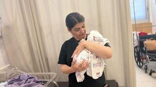 לינה מחזיקה את מילאר הקטן שנקרא על שם בנה שנהרג באסון מג'דל שמס 