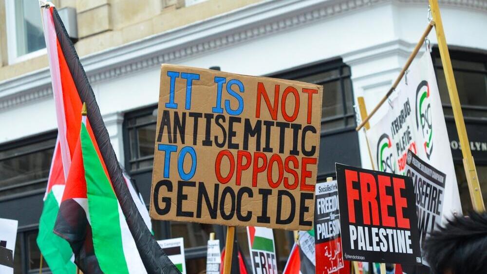 Надпись на плакате: "Противостоять геноциду - это не антисемитизм" 