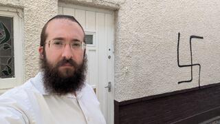 הרב בנצי אלפרוביץ' לצד הגרפיטי של צלב קרס שרוסס על ביתו