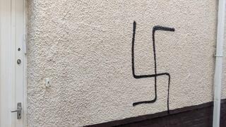 הרב בנצי אלפרוביץ' לצד הגרפיטי של צלב קרס שרוסס על ביתו