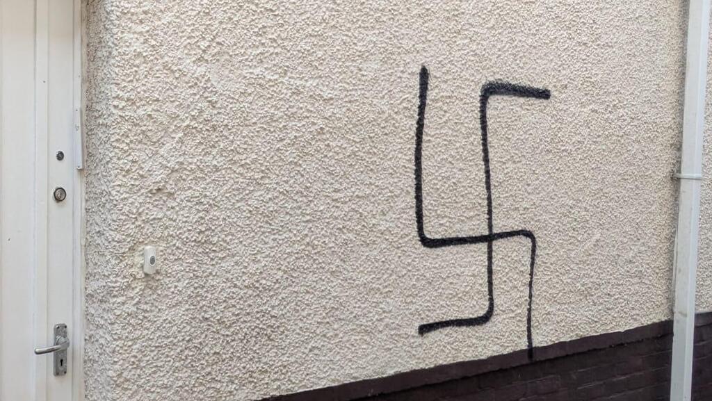 הרב בנצי אלפרוביץ' לצד הגרפיטי של צלב קרס שרוסס על ביתו