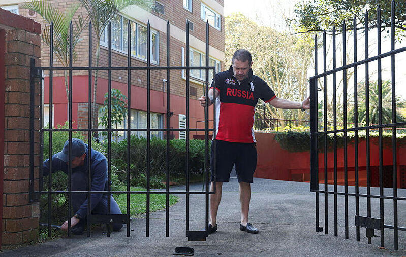 Russian consulate officials fix the damaged gate (Photo: Hollie Adams/Reuters) רכב התנגש בקונסוליה הרוסית בסידני