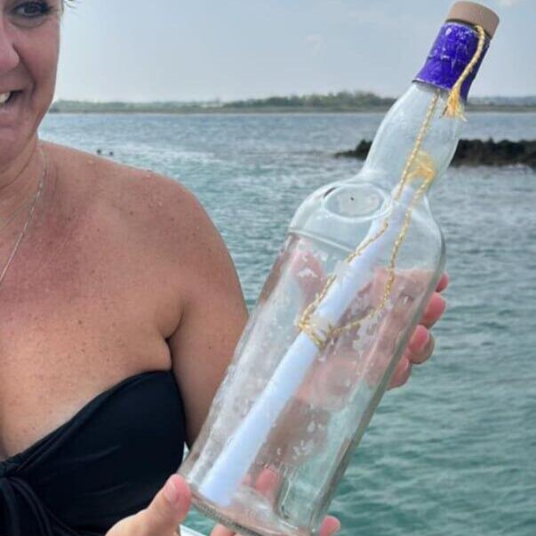 האישה האיטלקית אוחזת בבקבוק עם המכתב