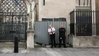 Security guards stand in front a screen covering a new mural by anonymous artist Banksy on the Royal Courts of Justice in London 