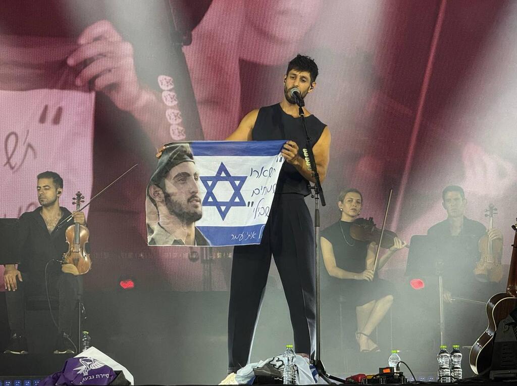 Idan Amedi holds up flags in memory of fallen soldiers during his concert in Park Yarkon עידן עמדי בפארק הירקון