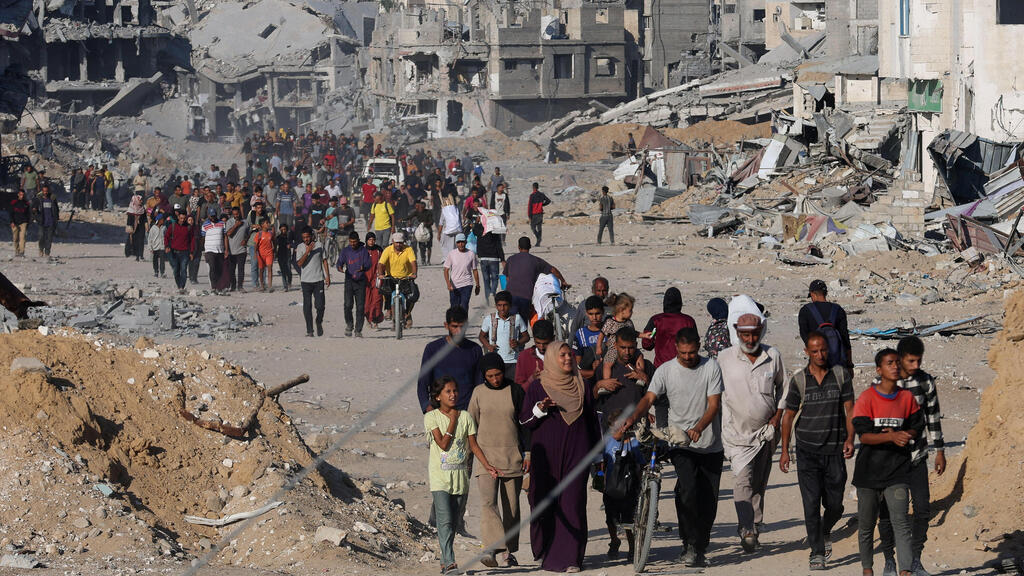 עקורים פלסטינים חולפים על פני הריסות