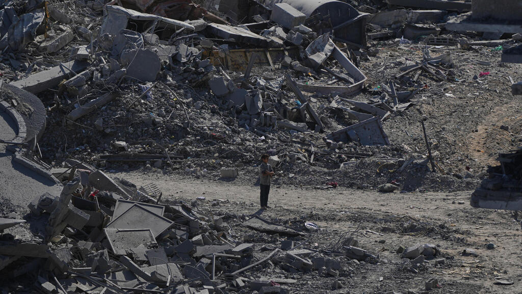 Displaced Palestinians walk among the ruins in Gaza (Photo: Abdel Kareem Hana/AP) עקורים פלסטינים חולפים על פני הריסות